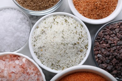 Photo of Different kinds of salt on white table, flat lay