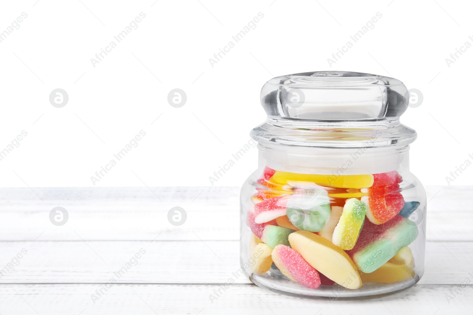 Photo of Tasty jelly candies in jar on white wooden table