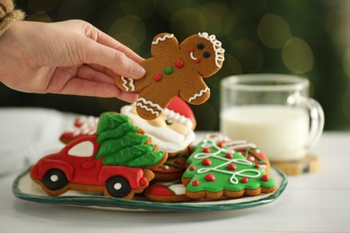 Photo of Woman with decorated Christmas cookies at table, closeup