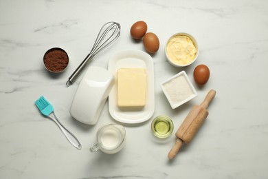 Photo of Flat lay composition with fresh butter among other products on white marble table