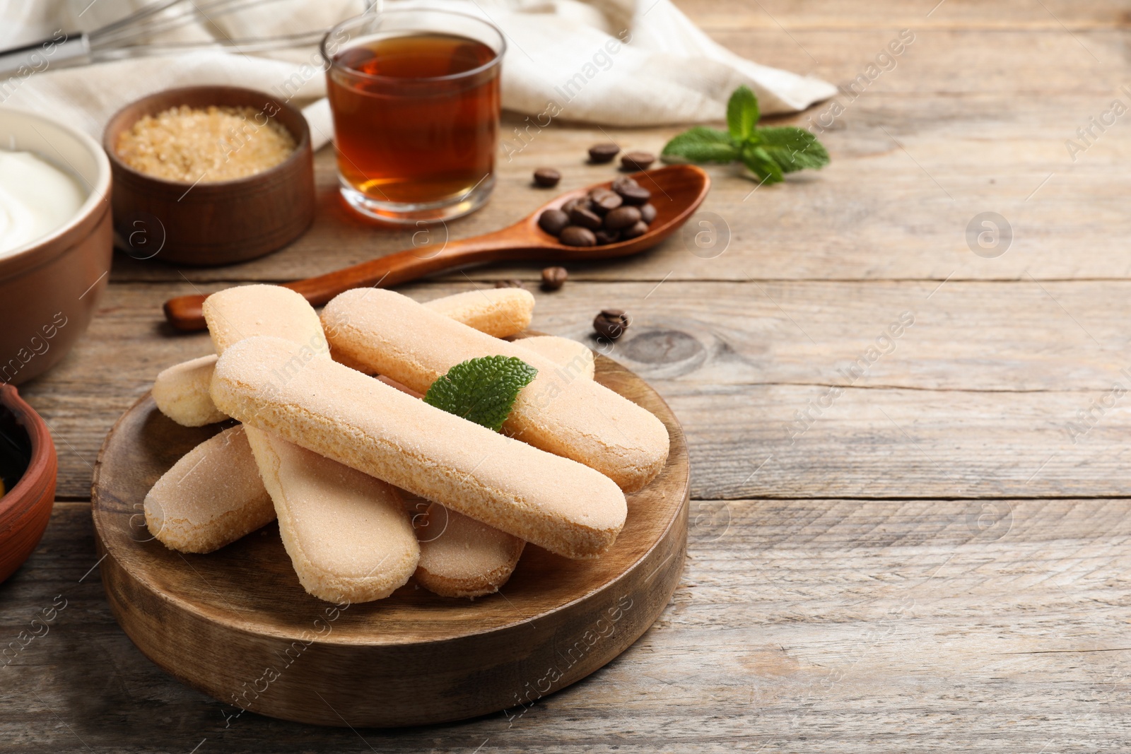 Photo of Tasty cookies and other tiramisu ingredients on wooden table, space for text