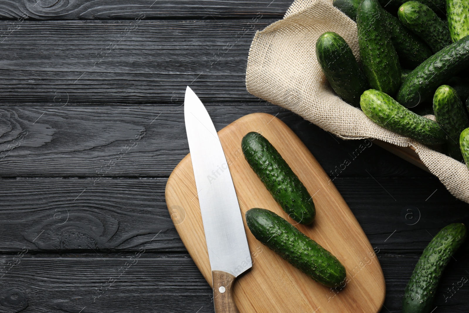 Photo of Fresh ripe cucumbers on dark wooden table, flat lay. Space for text