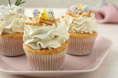 Photo of Tasty Easter cupcakes with vanilla cream on light table, closeup