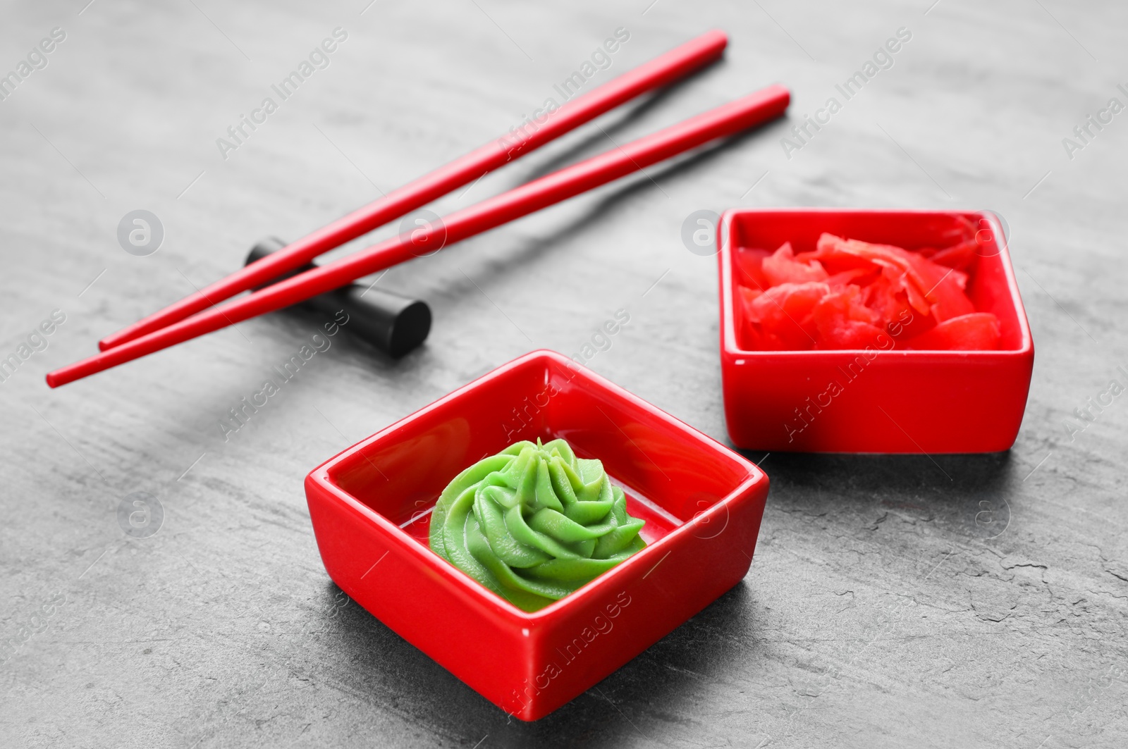 Photo of Swirl of wasabi paste, pickled ginger and chopsticks on grey table