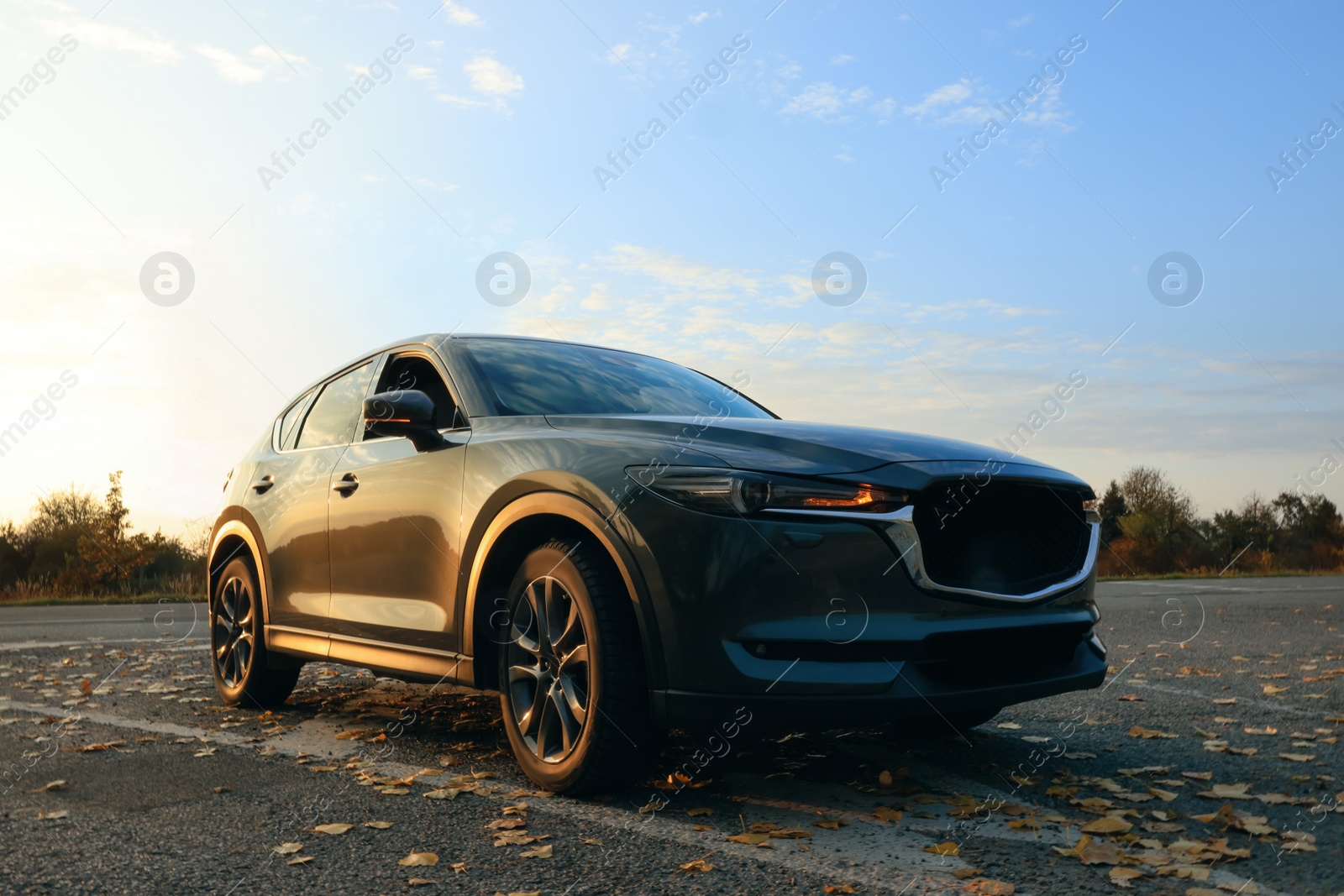 Photo of Black modern car parked on road at sunset