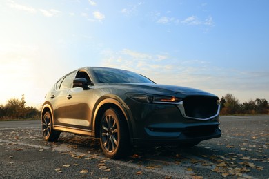 Photo of Black modern car parked on road at sunset