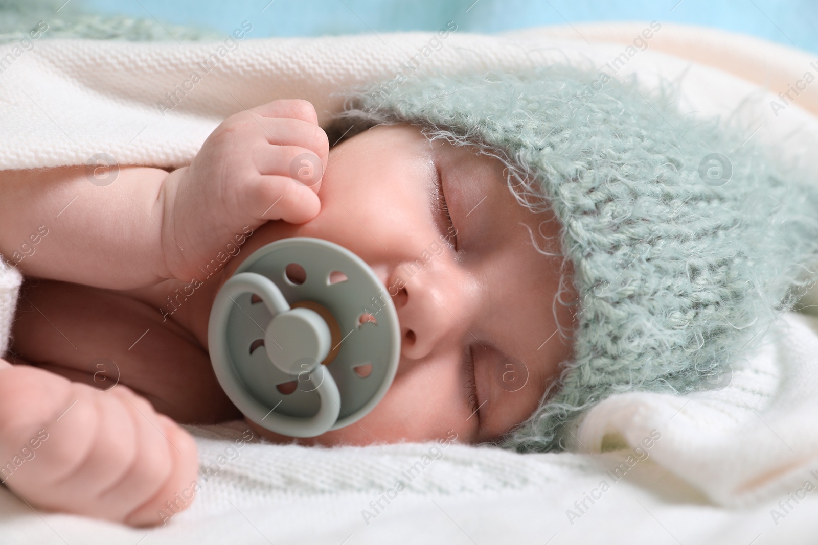 Photo of Cute newborn baby with pacifier sleeping on white blanket, closeup