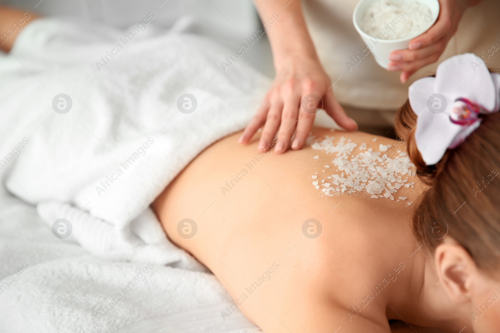 Photo of Beautiful young woman having massage with body scrub in spa salon