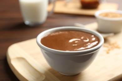 Photo of Bowl with caramel sauce on board, closeup