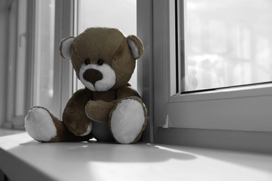 Photo of Cute teddy bear on windowsill indoors. Space for text