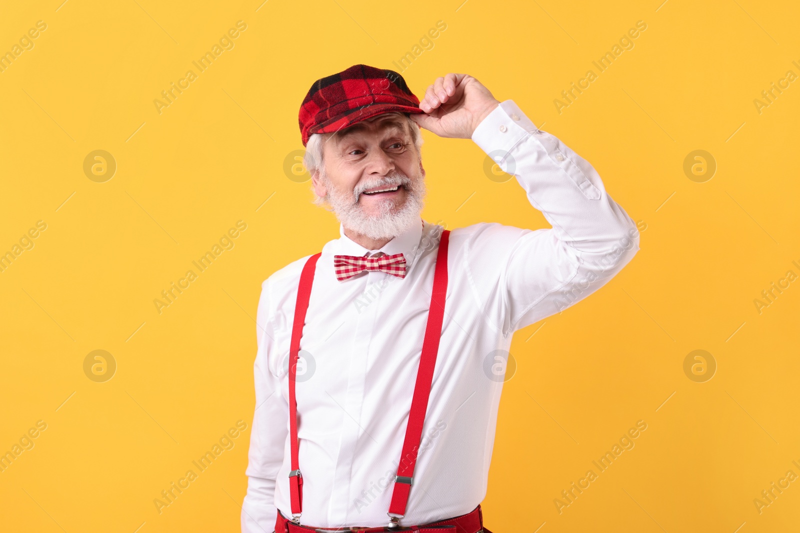 Photo of Portrait of grandpa with stylish hat and bowtie on yellow background