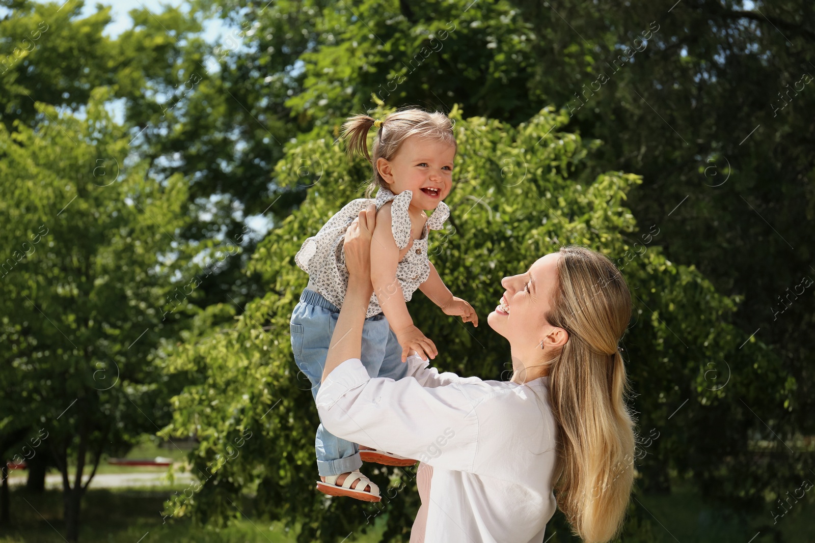 Photo of Happy mother with her daughter having fun in park. Space for text