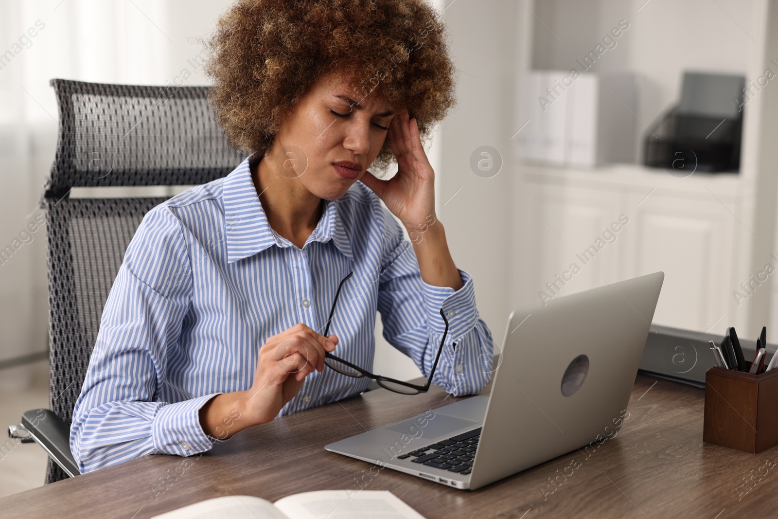 Photo of Woman suffering from headache at workplace in office