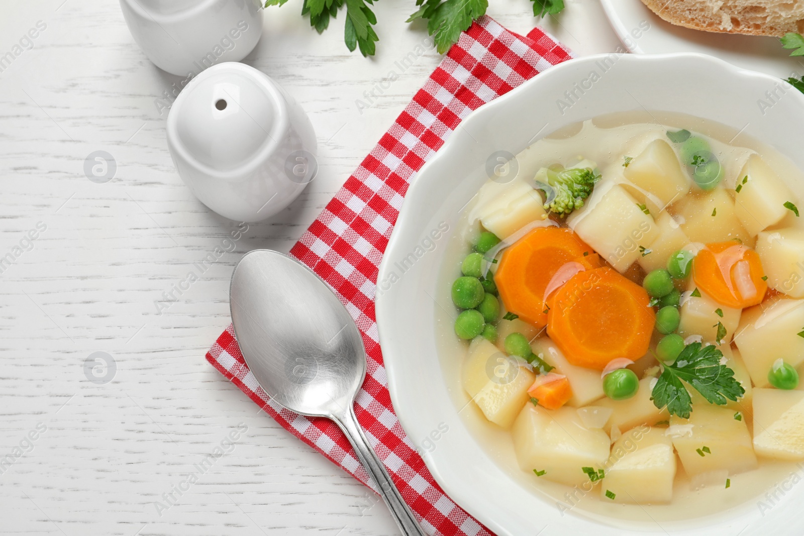 Photo of Bowl of fresh homemade vegetable soup served on white wooden table, flat lay. Space for text