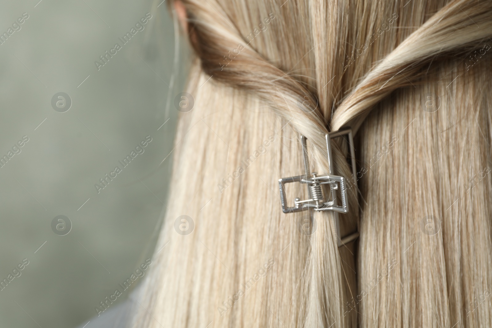 Photo of Young woman with beautiful hair claw on grey background, closeup