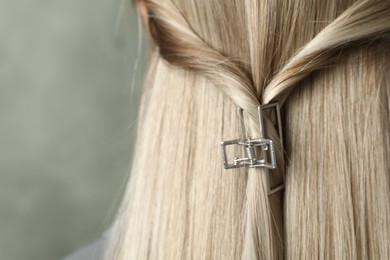 Photo of Young woman with beautiful hair claw on grey background, closeup