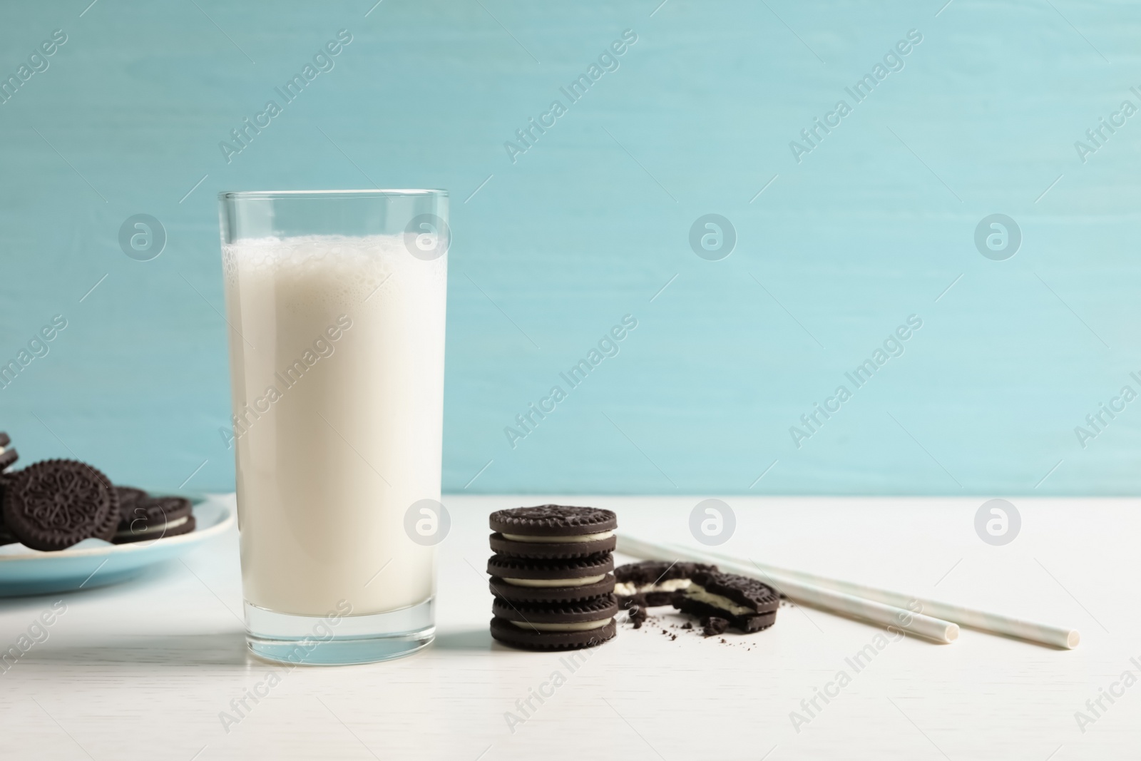 Photo of Glass of milk with chocolate cookies on table against color background. Space for text