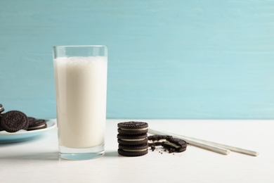 Photo of Glass of milk with chocolate cookies on table against color background. Space for text
