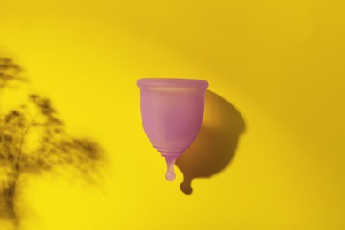 Menstrual cup on yellow background, top view