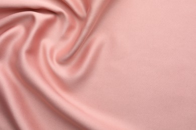 Crumpled pink silk fabric as background, top view. Space for text