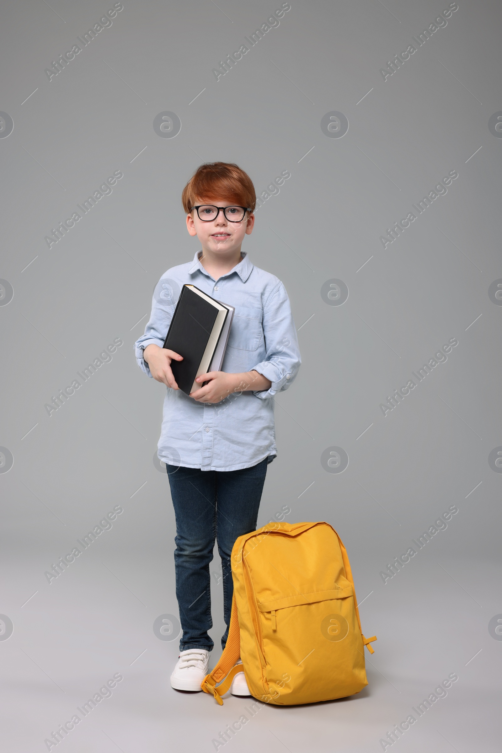 Photo of Happy schoolboy with books on grey background