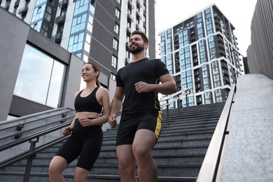 Photo of Healthy lifestyle. Happy couple running on steps outdoors, low angle view