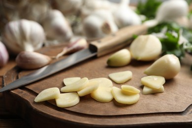 Photo of Fresh whole and cut garlic on wooden board, closeup. Organic product
