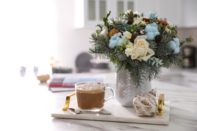 Photo of Beautiful winter wedding bouquet and cup of coffee on white marble table indoors