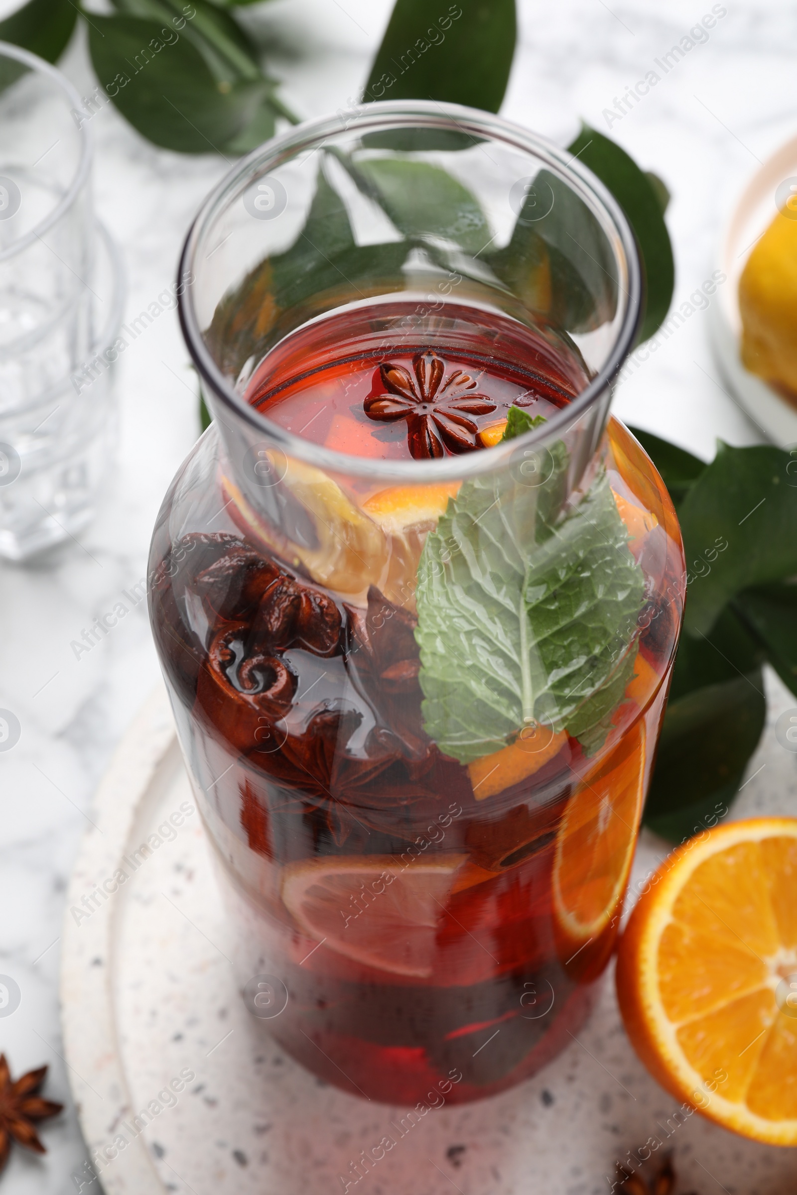 Photo of Delicious punch drink in bottle on white table, closeup