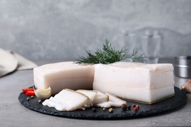 Photo of Pork fatback with spices served on grey table