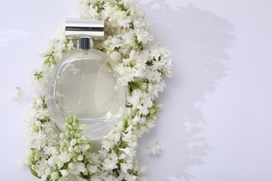 Luxury perfume and floral decor on white background, top view. Space for text