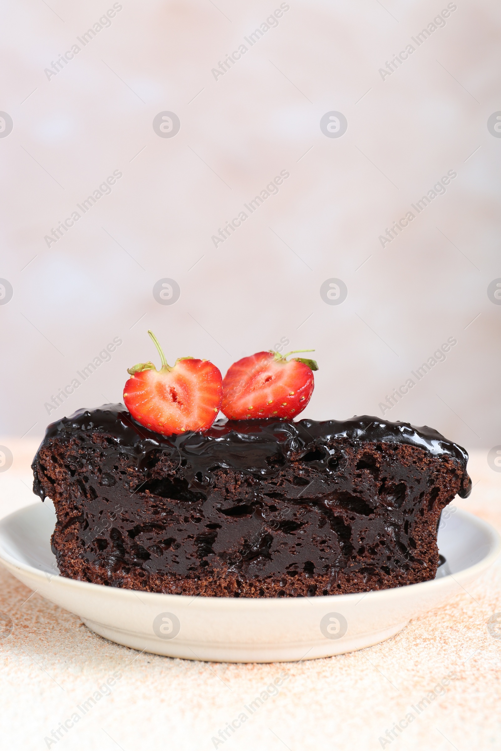 Photo of Piece of chocolate sponge cake with strawberry on beige textured table