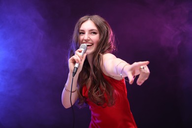 Emotional woman with microphone singing in color lights