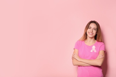 Woman with silk ribbon and space for text on color background. Breast cancer awareness concept