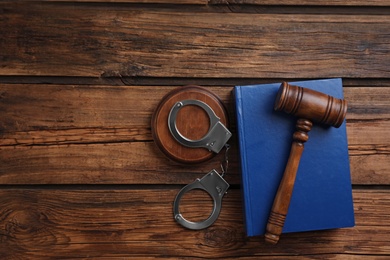 Photo of Flat lay composition with handcuffs and gavel on wooden table, space for text. Criminal law