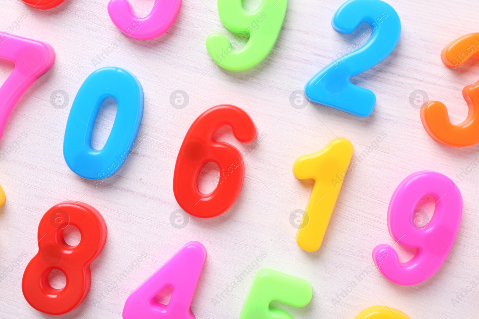 Photo of Colorful numbers on white wooden school desk, flat lay