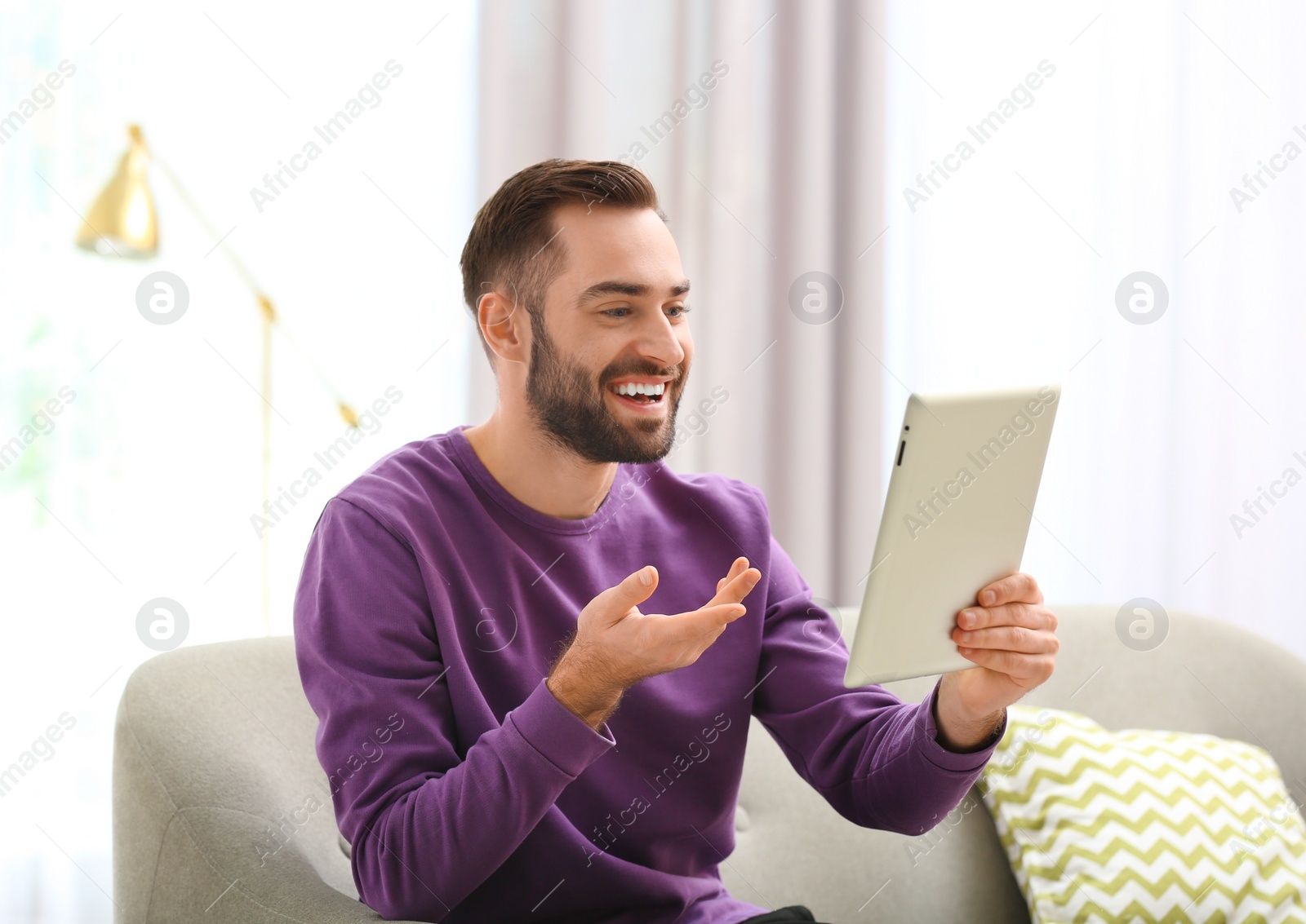 Photo of Man using tablet for video chat in living room