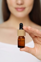 Photo of Woman holding bottle of essential oil, closeup