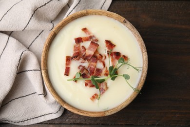 Delicious potato soup with bacon and microgreens in bowl on wooden table, top view