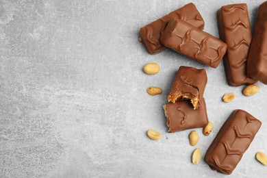 Photo of Chocolate bars with caramel, nuts and nougat on light grey table, flat lay. Space for text