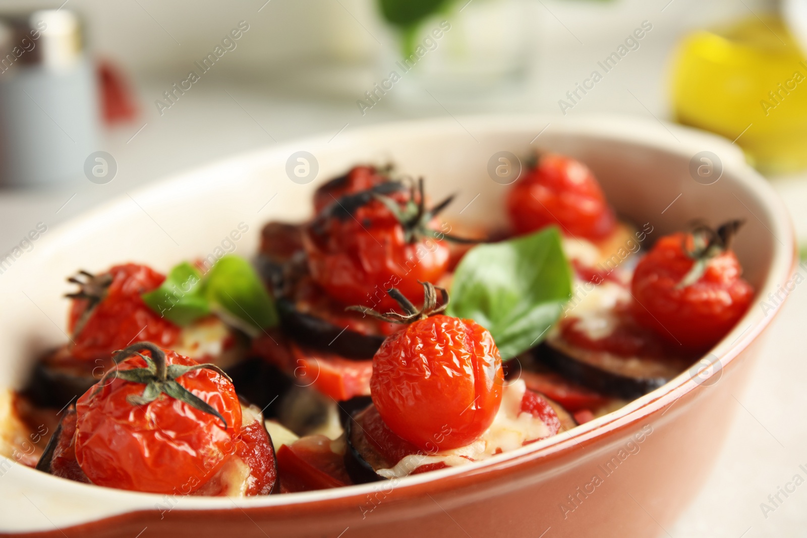 Photo of Baked eggplant with tomatoes, cheese and basil in dishware on table, closeup