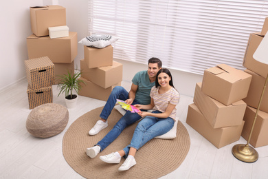 Happy couple with color palette samples in their new flat on moving day, above view