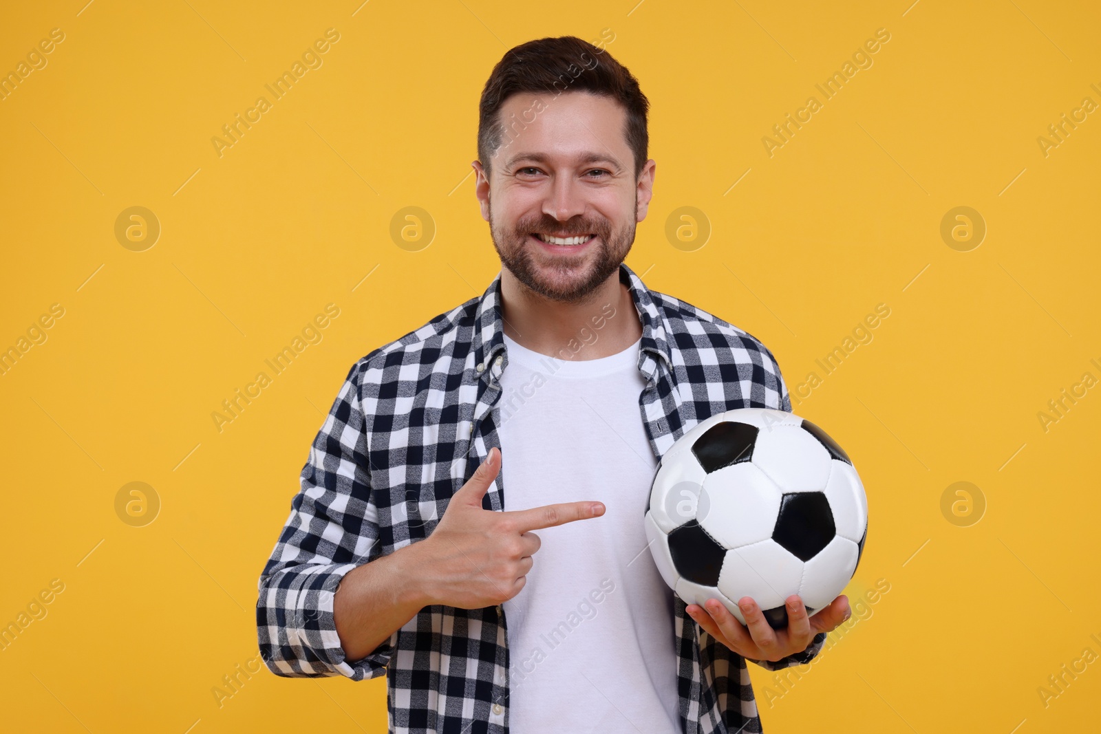 Photo of Happy sports fan with ball on yellow background