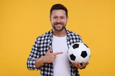 Happy sports fan with ball on yellow background