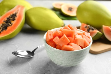 Photo of Fresh diced papaya in bowl on light grey table, closeup