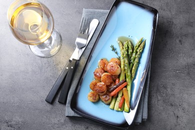 Photo of Delicious fried scallops with asparagus served on grey table, flat lay