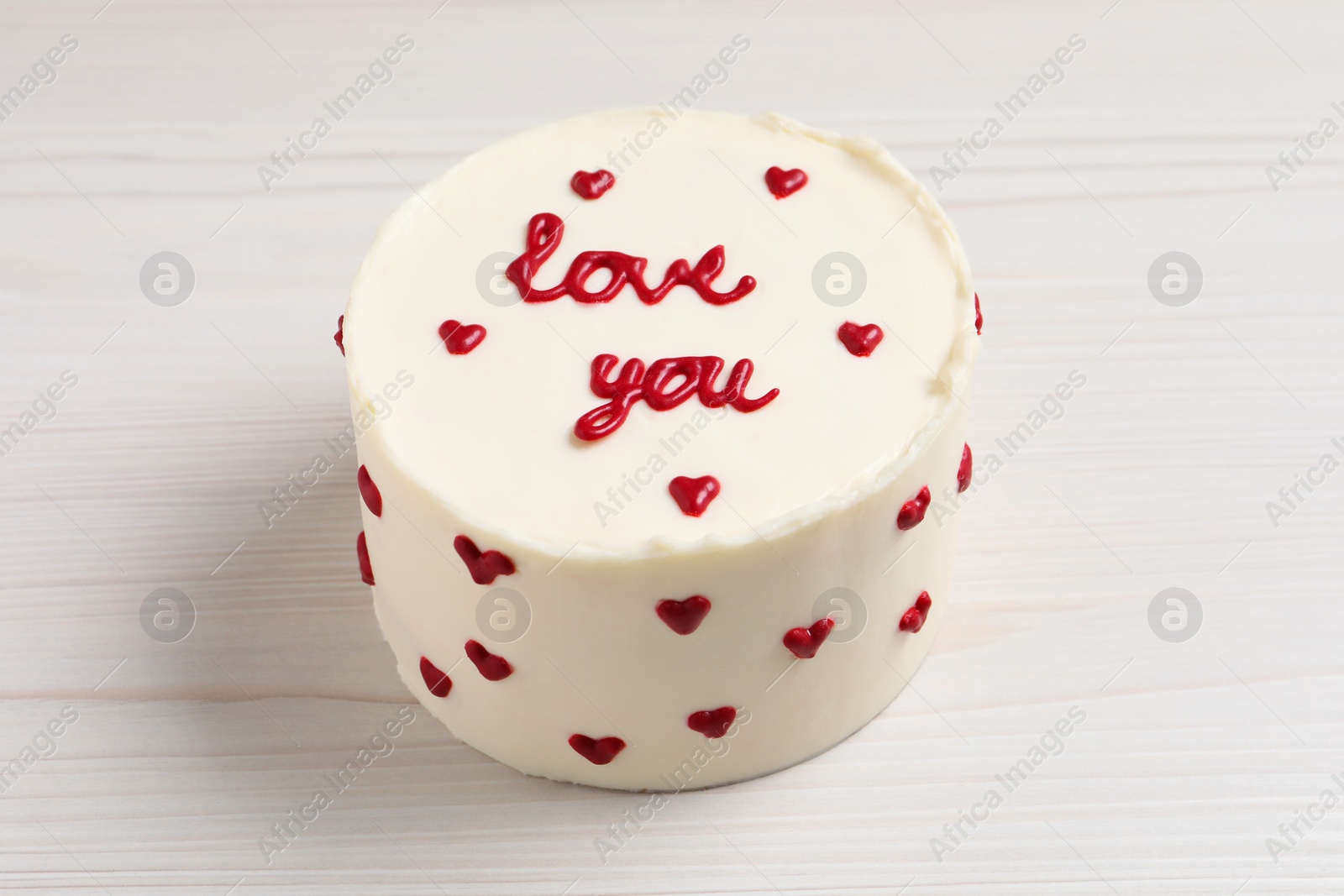 Photo of Bento cake with text Love You on white wooden table. St. Valentine's day surprise