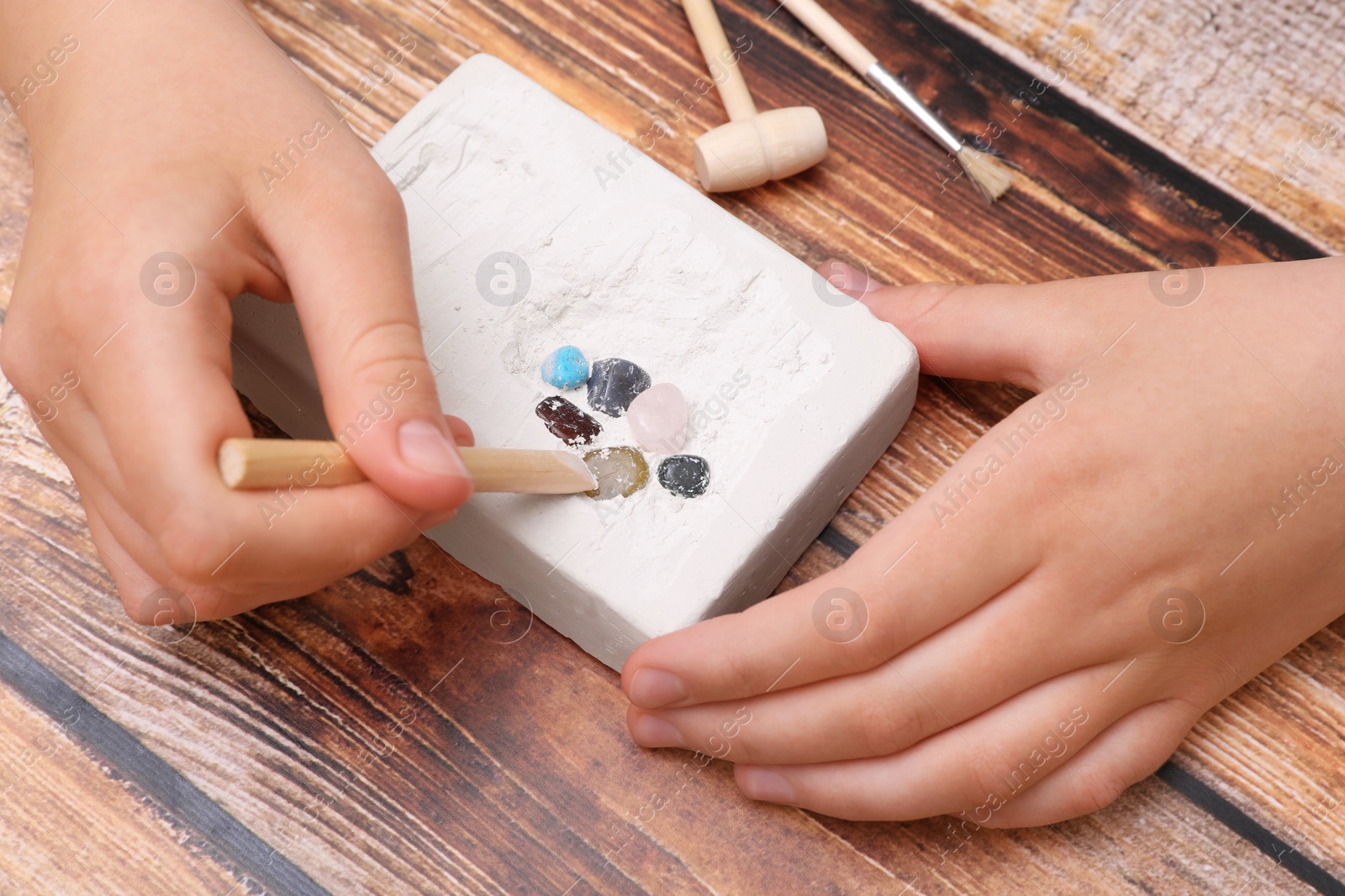 Photo of Child playing with Excavation kit at wooden table, above view. Educational toy for motor skills