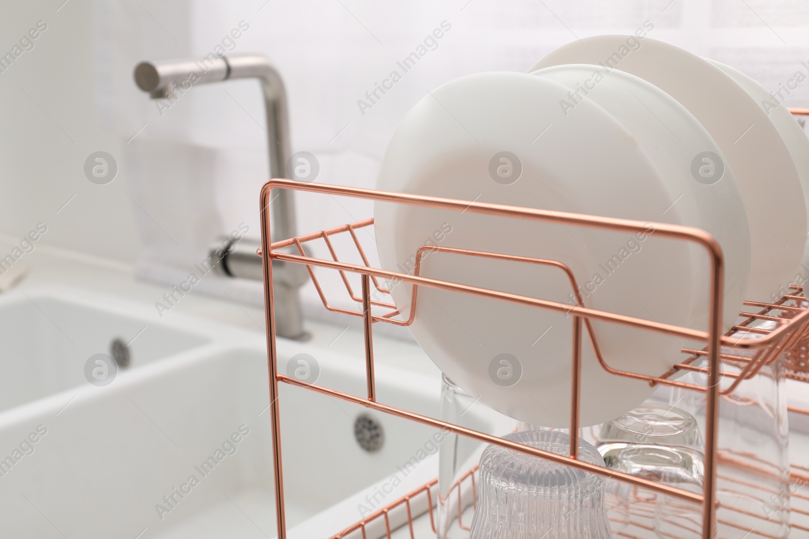 Photo of Drying rack with clean dishes near sink in kitchen, closeup