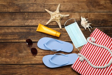 Photo of Stylish bag and beach accessories on wooden background, flat lay